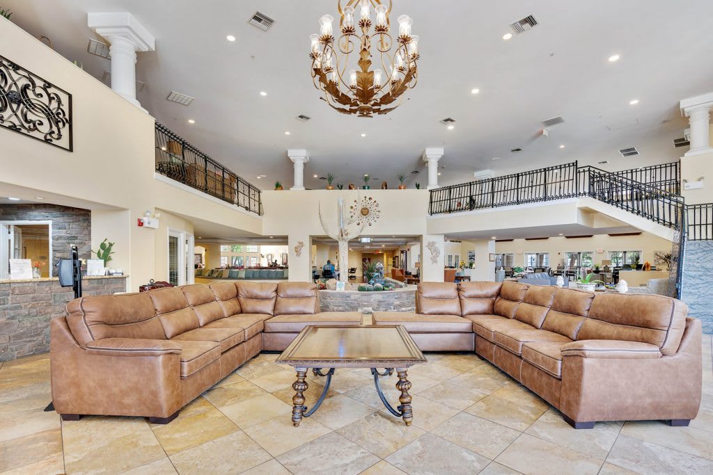 A spacious lobby with leather sofas, a large chandelier, and tiled flooring.