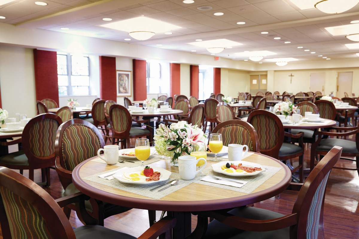 A well-arranged dining room with tables set for breakfast, featuring flowers in the center.