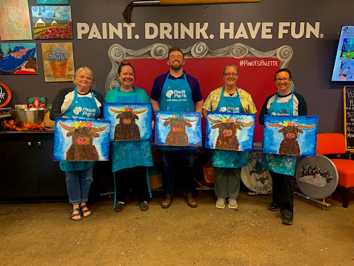 Participants proudly display their artwork after a fun paint and sip class.