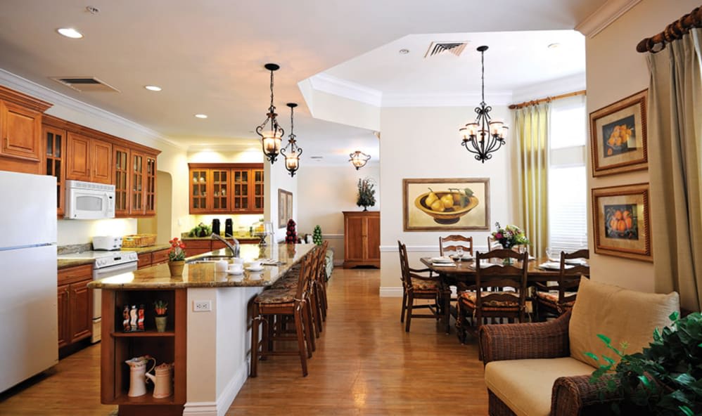 A modern open-plan kitchen and dining area with elegant chandeliers and wood flooring.
