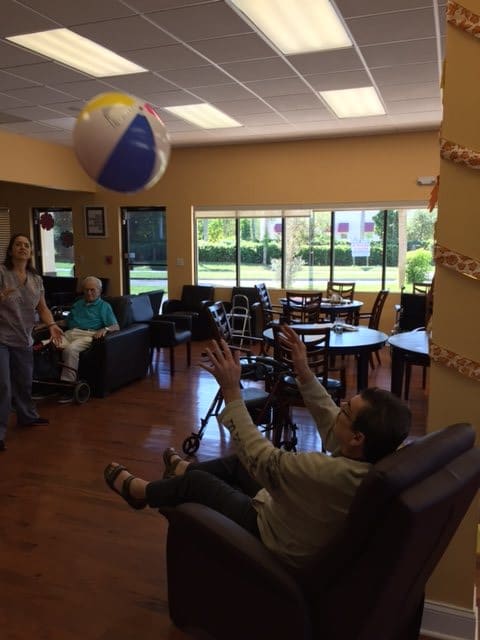 Seniors enjoying a recreational activity with a beach ball indoors.