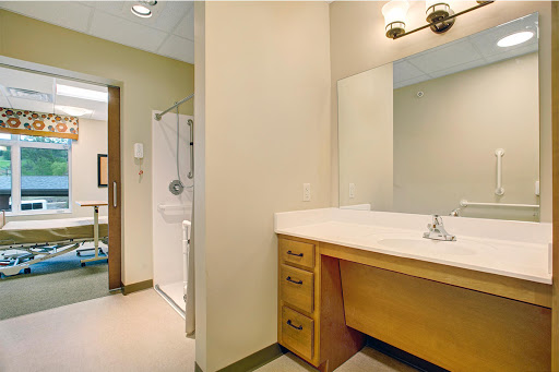 A well-lit bathroom featuring a sink vanity, mirror, and shower.