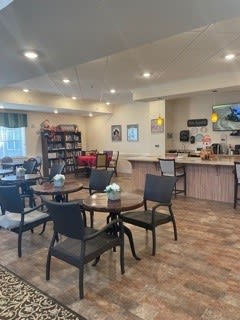 A cozy cafe interior with tables, chairs, a bookshelf, and a coffee station.