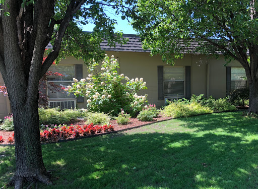A beautifully landscaped front yard featuring vibrant flowers and lush greenery surrounding a charming house.