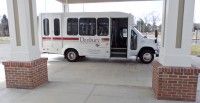 A white shuttle bus parked at a station.