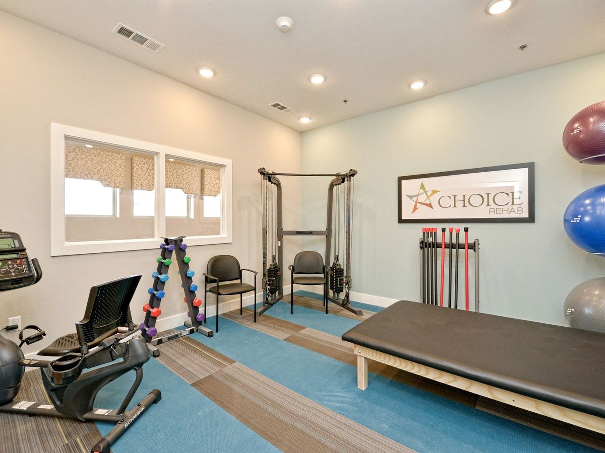 A well-equipped rehabilitation room with exercise equipment and a comfortable treatment area.