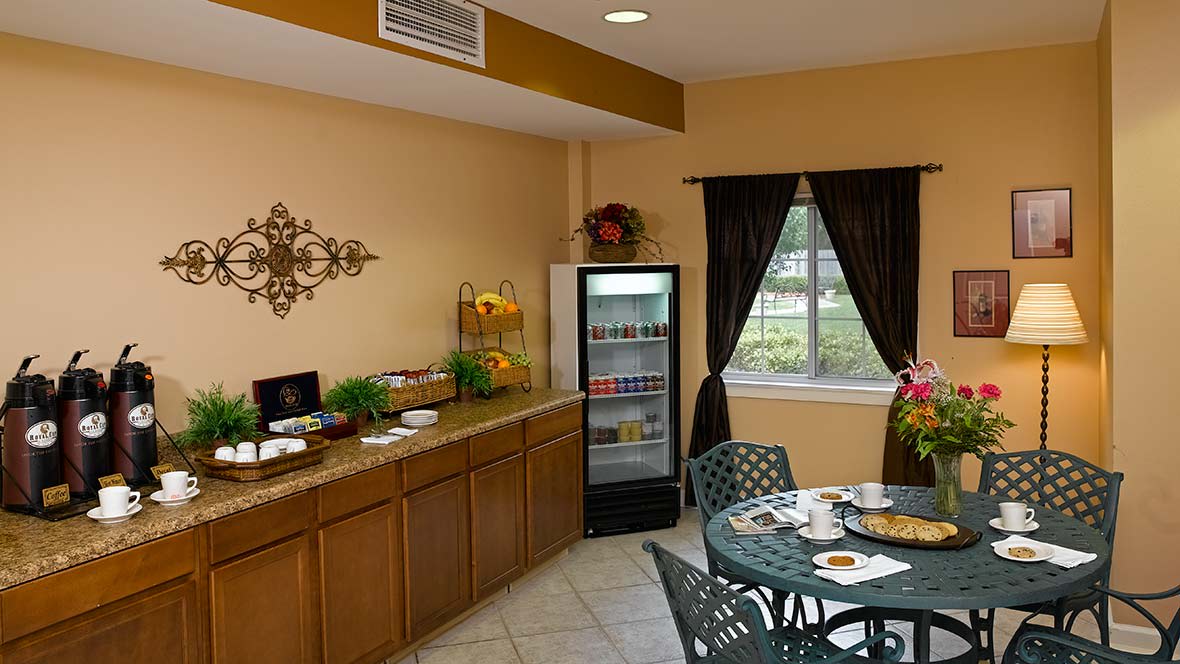A cozy dining area with a small refrigerator, decorative elements, and a table set for breakfast.