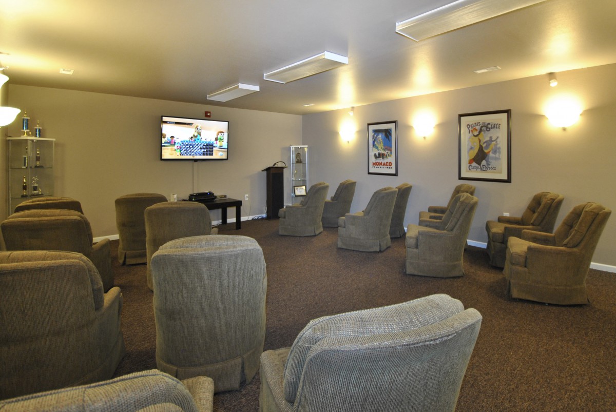 A comfortable lounge area with multiple chairs facing a wall-mounted television.