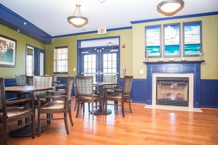 A bright dining room with tables, chairs, and a fireplace.