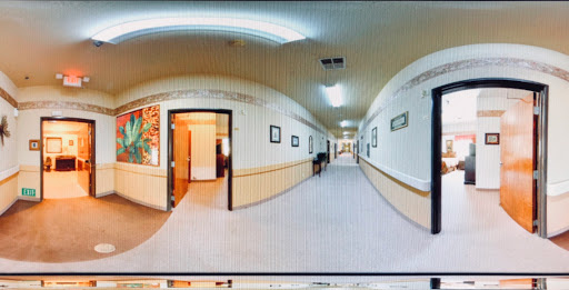 A panoramic view of an interior hallway featuring doors and framed artwork on the walls.