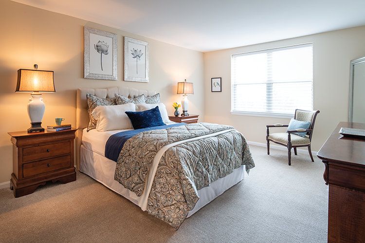 A cozy bedroom with a neatly made bed, decorative pillows, and warm lighting.