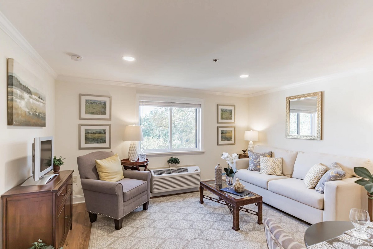 A cozy and elegantly decorated living room with a sofa, armchair, coffee table, and large window.