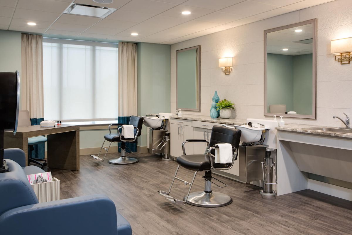 A modern and empty hair salon with chairs and mirrors.