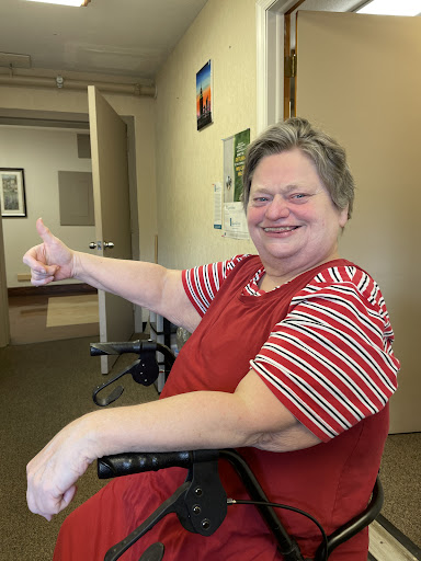 A cheerful woman in a wheelchair giving a thumbs up, showcasing positivity and joy.