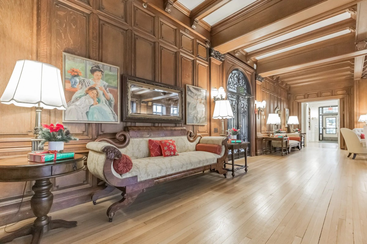 A luxurious vintage living room featuring wood paneling, classic furniture, and artwork adorning the walls.
