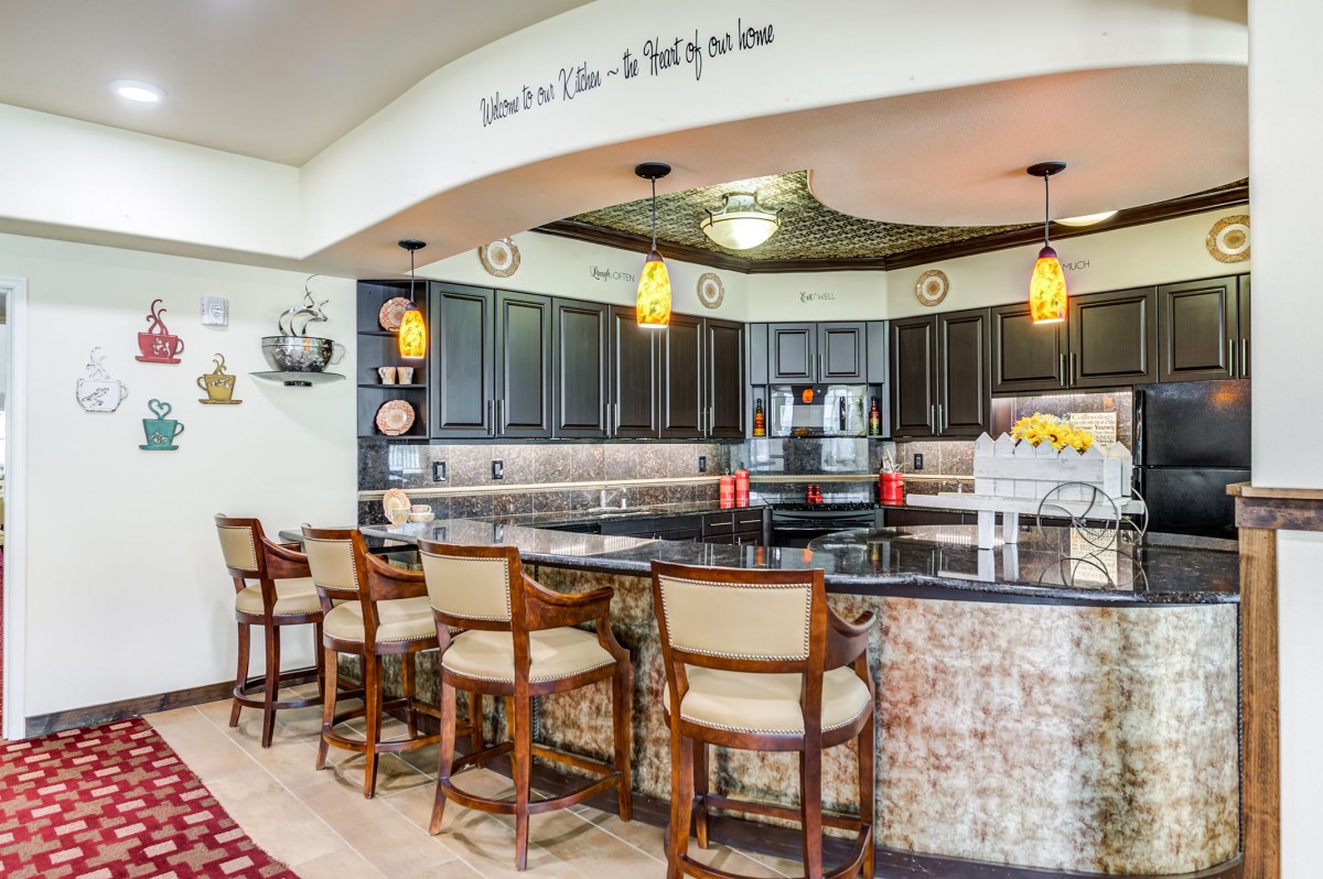 A modern kitchen with a bar counter, pendant lights, and stylish decor.