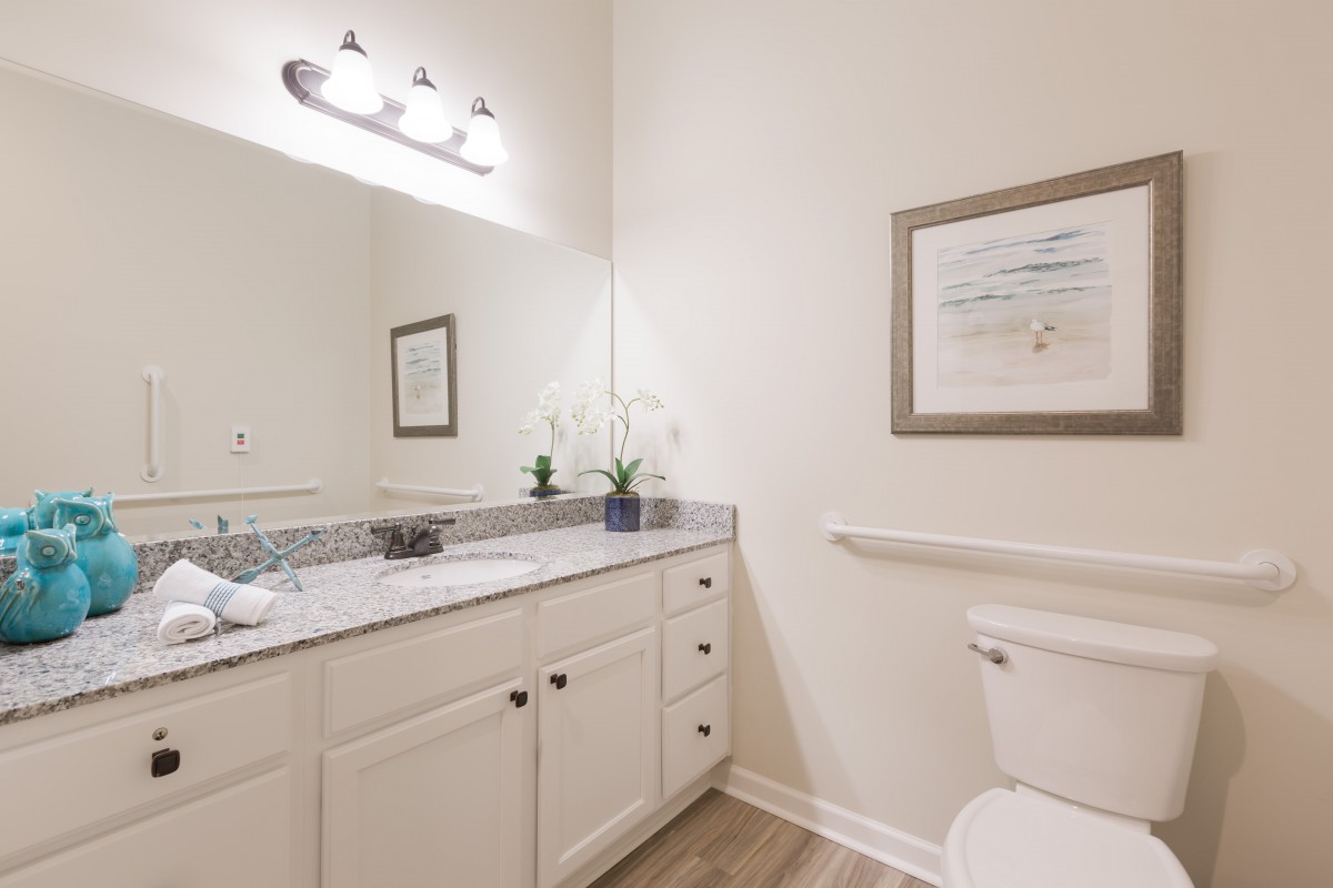 A clean and modern bathroom with a vanity, mirror, and toilet.