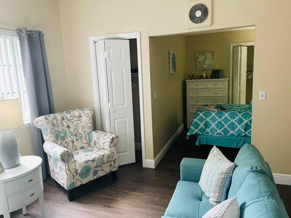A cozy living space with a blend of a bedroom and sitting area featuring floral armchairs and a teal sofa.