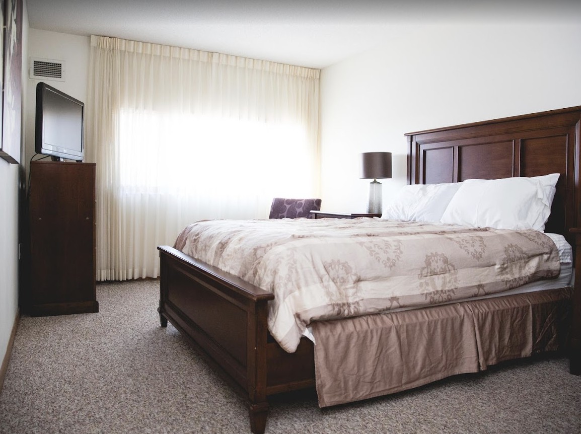 A cozy bedroom with a large bed, wooden furniture, and soft natural lighting.