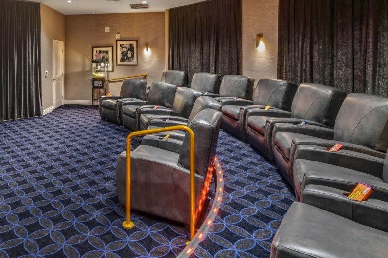 Luxury theater seating with recliners and a handrail for accessibility.