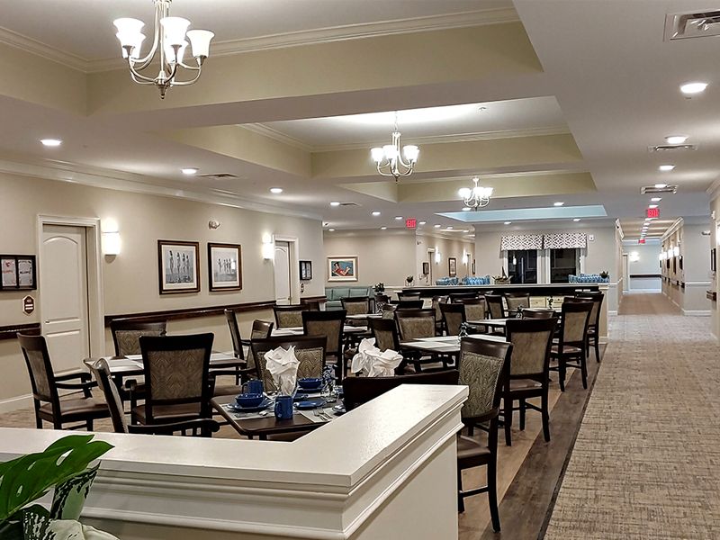 A spacious and elegantly designed dining area with neatly arranged tables and chairs under soft lighting.