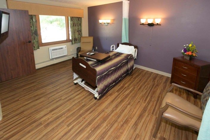 A clean and organized hospital room with a single bed and modern amenities.