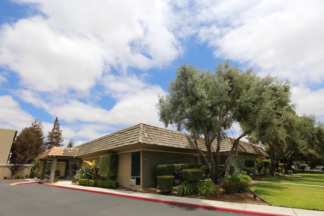 A suburban building with a tiled roof, surrounded by trees under a partly cloudy sky.