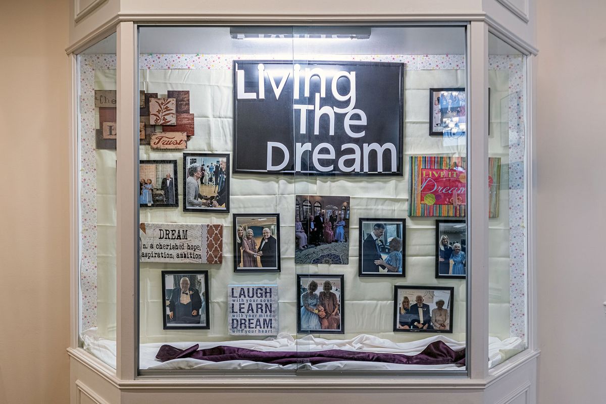 A display case showcasing a collection of photographs and inspirational signs centered around the theme 'Living the Dream'.