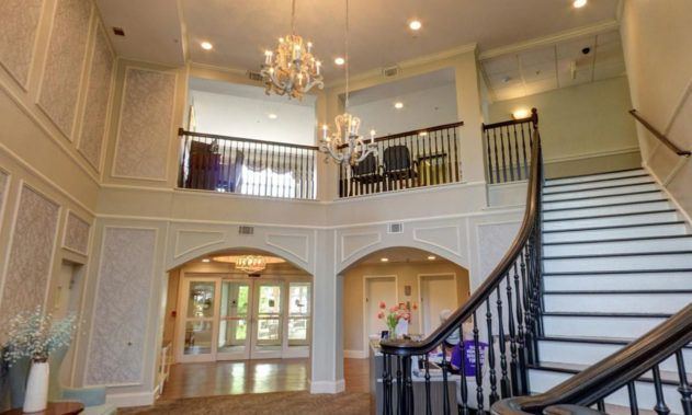 A spacious and elegant living area featuring a grand staircase and a chandelier.