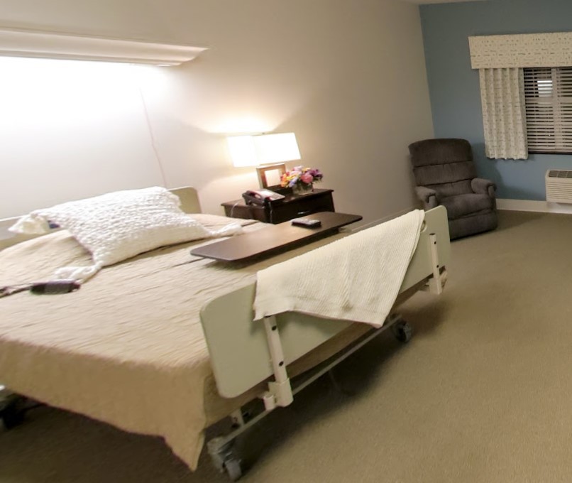 A hospital room featuring a bed and a side table with a lamp, creating a comfortable environment.