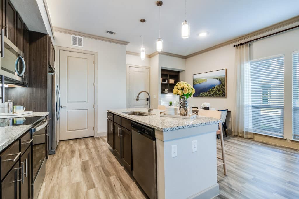 A modern kitchen interior featuring an island with a wooden floor and stylish lighting.