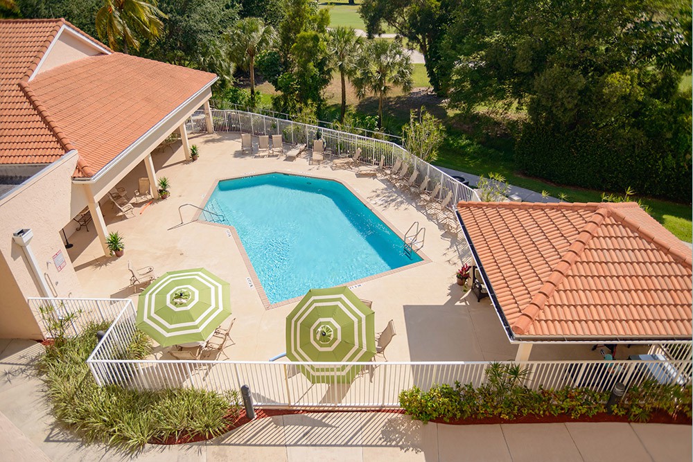 Aerial view of an outdoor swimming pool with surrounding lounge chairs and umbrellas.