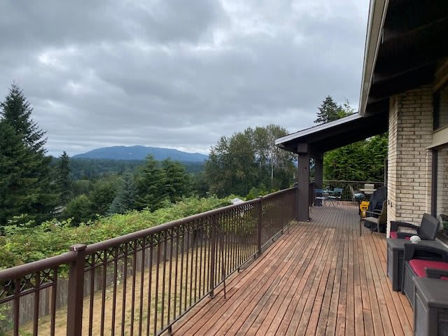 A wooden deck overlooking a scenic mountain view under a cloudy sky.
