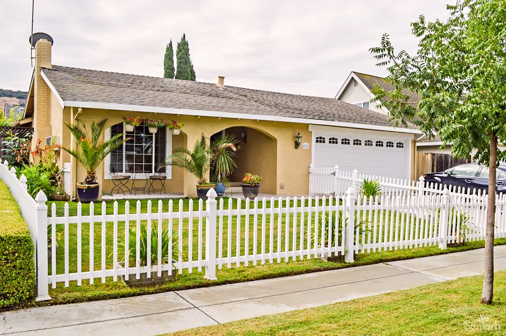 Suburban house with a white picket fence and well-manicured lawn.