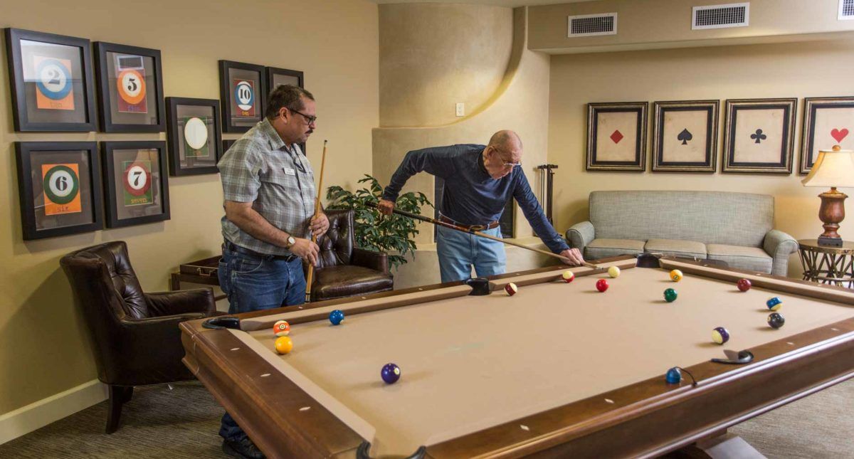 Two men enjoy a game of billiards in an indoor setting.