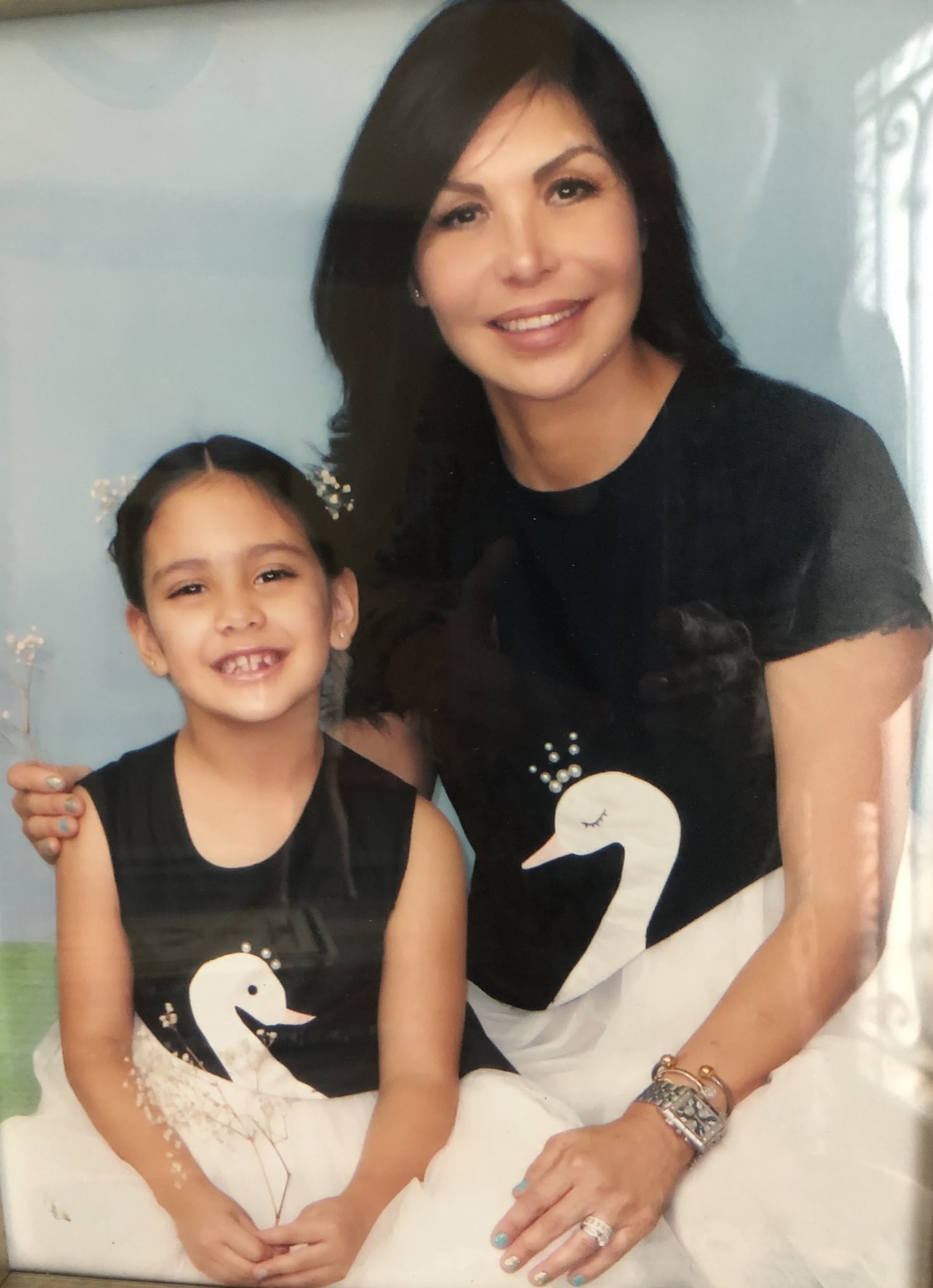 A mother and daughter wearing matching swan outfits, smiling together.
