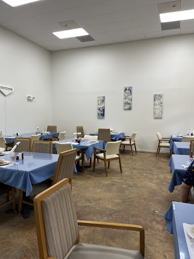 A spacious and inviting dining area featuring neatly arranged tables with blue tablecloths.