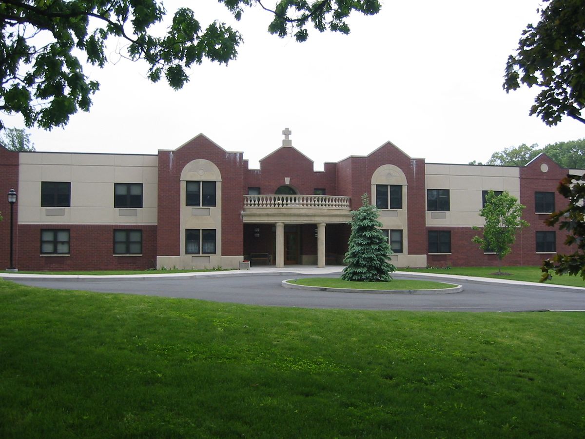 A front view of a school building with a manicured lawn and trees.
