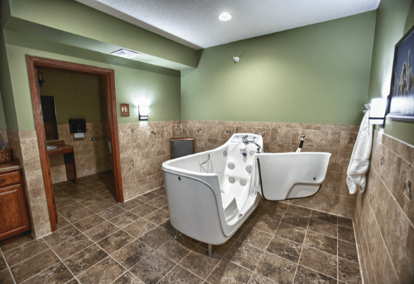 Spacious bathroom with a walk-in bathtub and green walls.