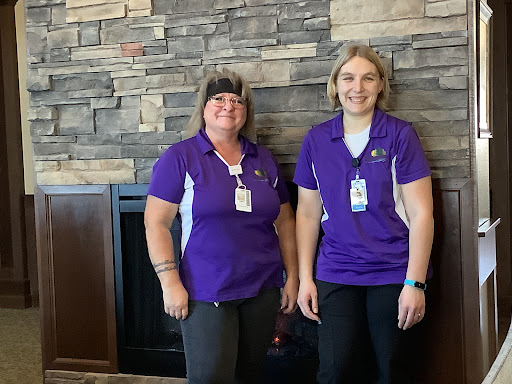 Two staff members posing together in a welcoming indoor setting.