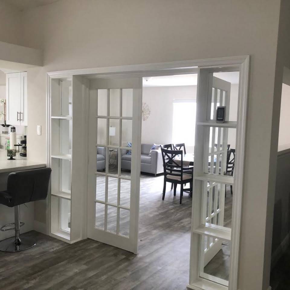 A modern living space featuring an open floor plan with French doors leading to a dining area.