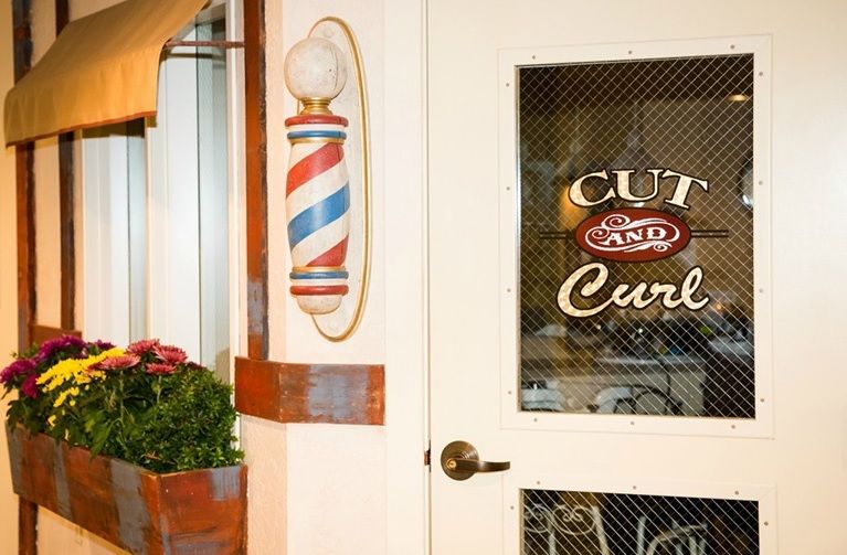A barbershop entrance with a classic barber pole and decorative signage on the door.