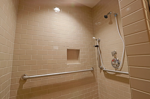 A modern shower space featuring beige tiles and accessibility grab bars.