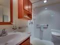 A small bathroom featuring a shower, sink, and wooden cabinets.