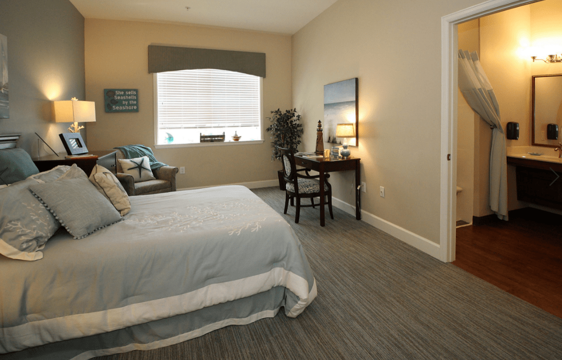 A modern bedroom with a comfortable bed, a desk, and various decorative elements.