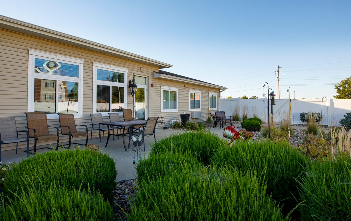 A well-maintained backyard with a patio area and outdoor seating, surrounded by lush greenery.