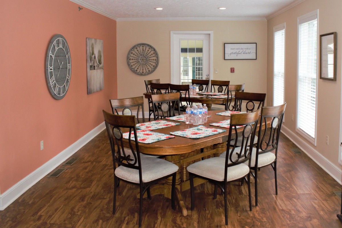 A cozy dining room with a wooden table and chairs, accented by wall decorations.
