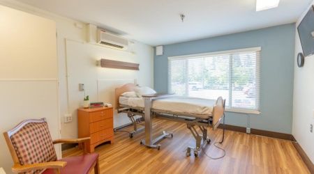 A clean and well-lit hospital room with a bed and window view.