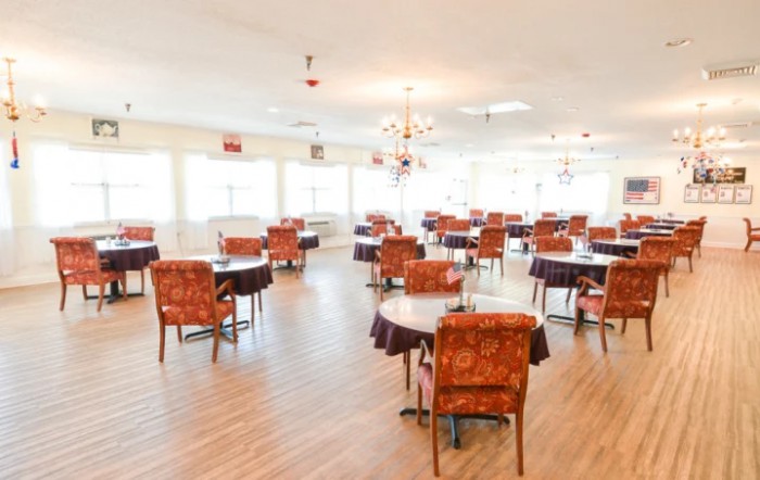 An empty dining area with tables and chairs arranged on a wooden floor.