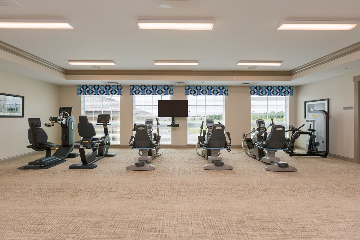 A spacious gym with various exercise machines and cardio equipment lined up in a well-lit room.